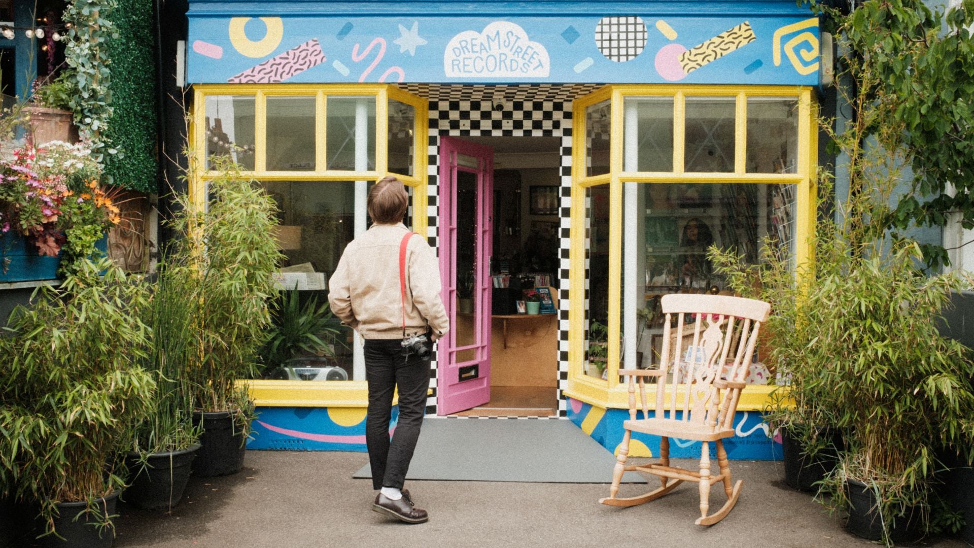 Photographer Charlie Richards stands outside Dream Street Records looking up at the colourful sign above the door